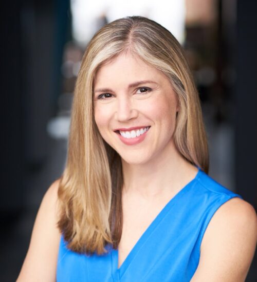 A woman in blue shirt smiling for the camera.