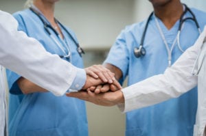 Two doctors holding hands in a circle