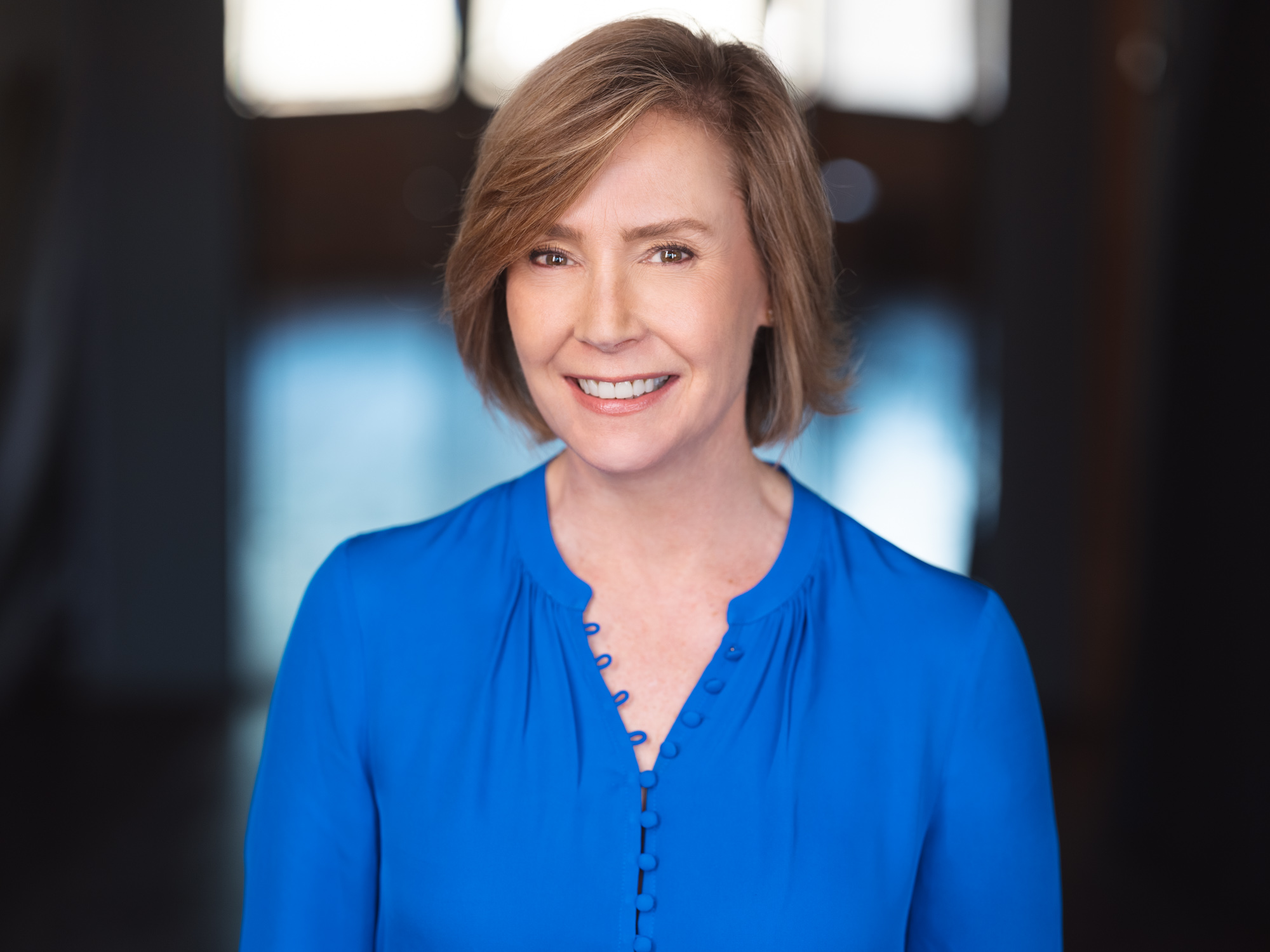A woman in blue shirt smiling for the camera.