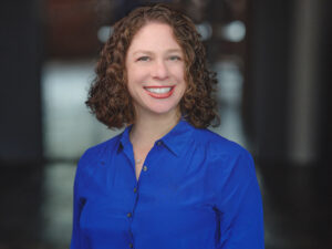 A woman with curly hair wearing a blue shirt.