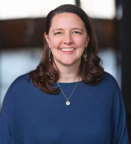 A woman in blue shirt smiling for the camera.