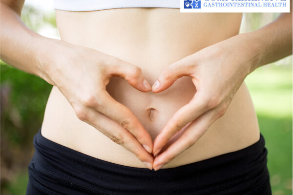 Woman making a heart shape with her hands on her stomach.