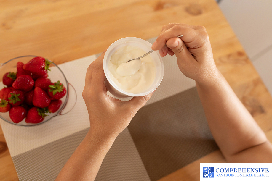 Holding a spoonful of creamy yogurt beside a bowl of fresh strawberries, suitable for a full liquid diet.