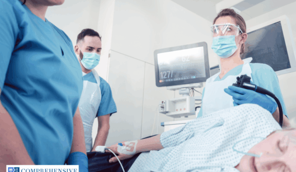 patient-asleep-during-colonoscopy-with-medical-team Patient lying sideways asleep during colonoscopy with doctors and nurses in operating room